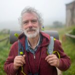 Senior man enjoying a misty hike in the countryside of Portugal, embodying adventure and vitality.